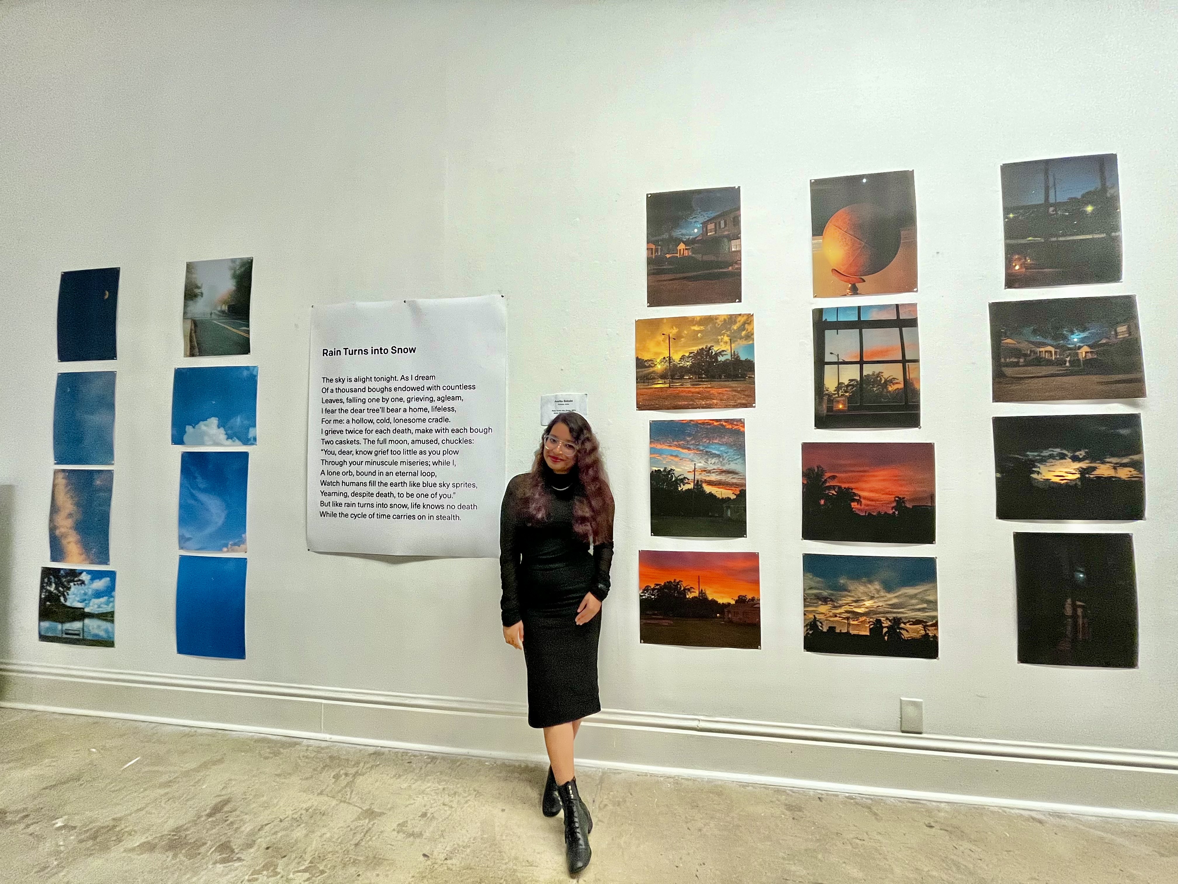 Amrita Bakshi beside her exhibited poem Rain Turns into Snow and her sky photographs