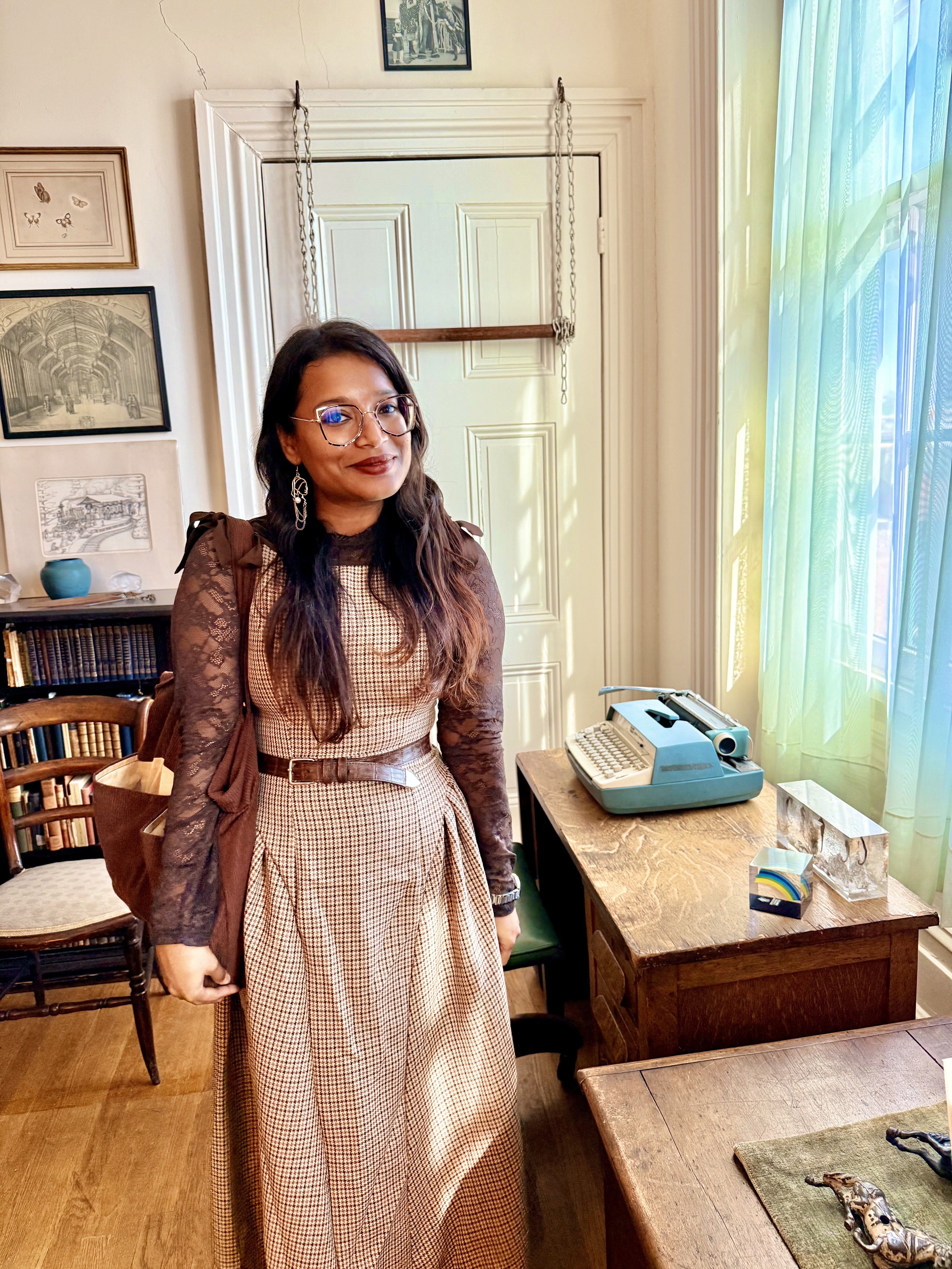 Amrita Bakshi in Marianne Moore's recreated writing room beside the blue typewriter Moore wrote on